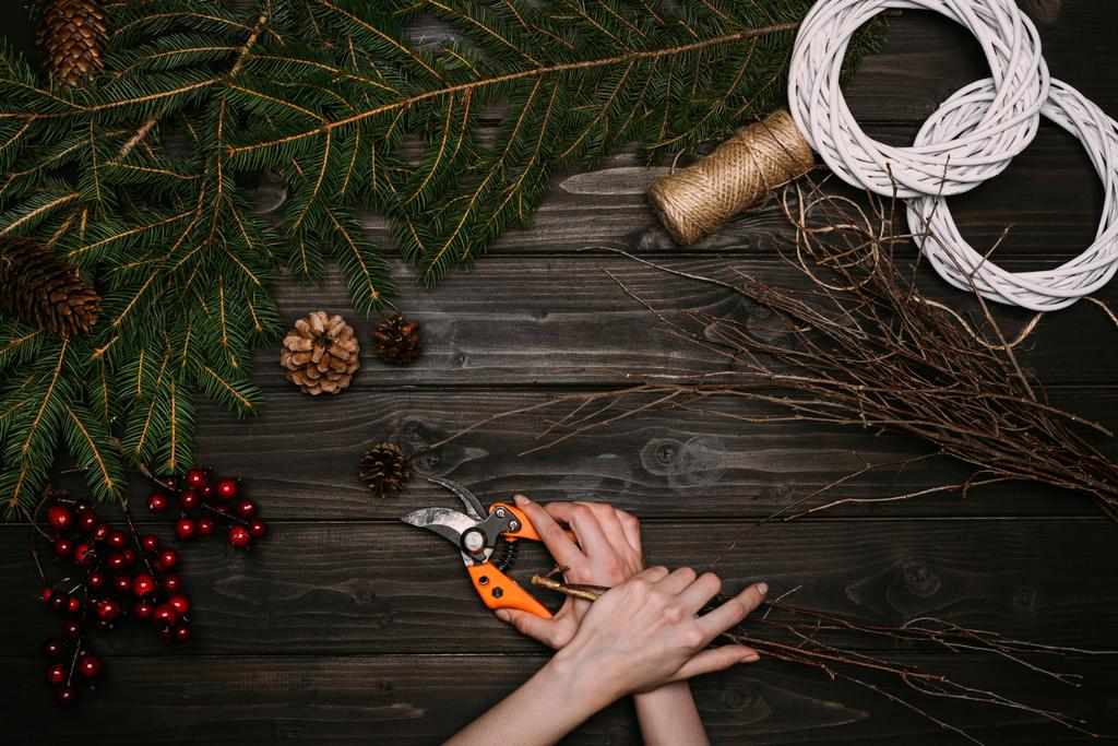 ανθοκόμος κάνει Χριστούγεννα στεφάνι με κλαδιά  - Φωτογραφία, εικόνα