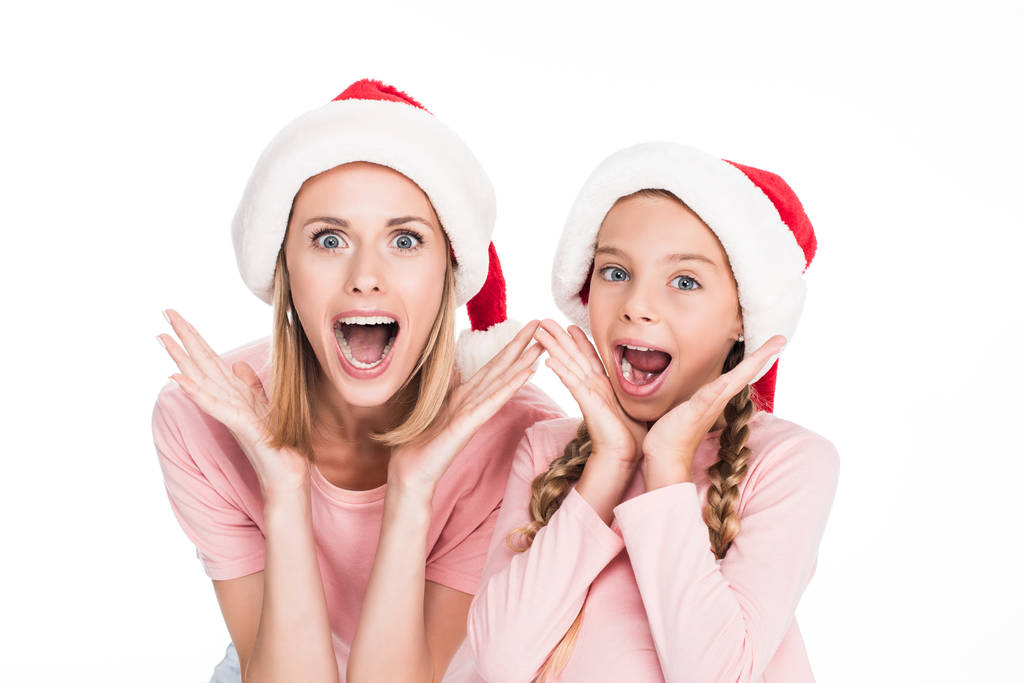 aufgeregte Mutter und Tochter in Weihnachtsmannmützen - Foto, Bild