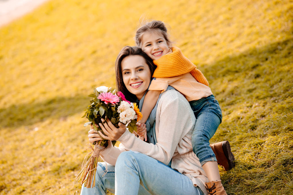 Woman holding flowers with daughter  - Photo, Image