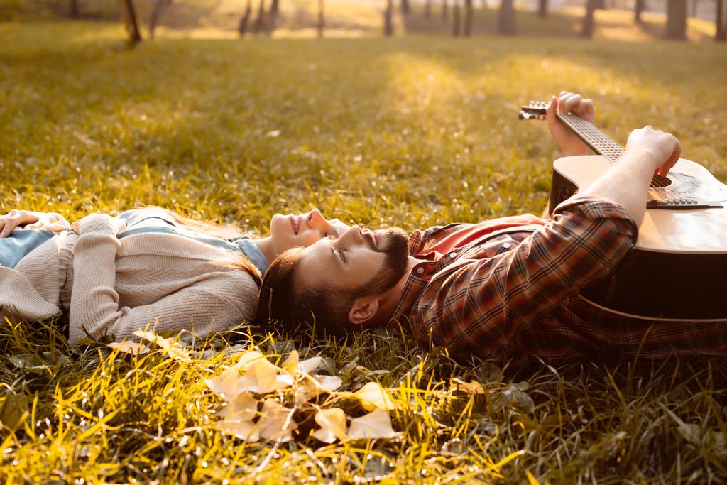 Couple lying on grass with guitar - Photo, Image