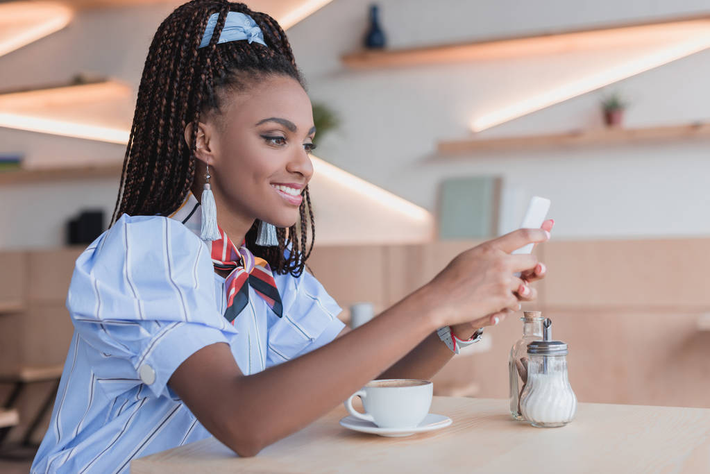 african american woman using smartphone in cafe - Photo, Image