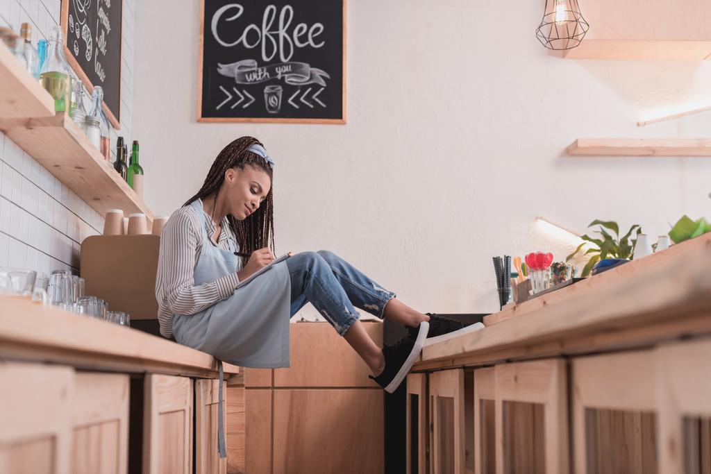 barista sitting on counter with notebook - Photo, Image