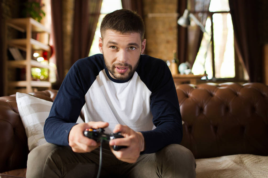 Юная брюнетка-мужчина играет в видеоигры дома
. - Фото, изображение