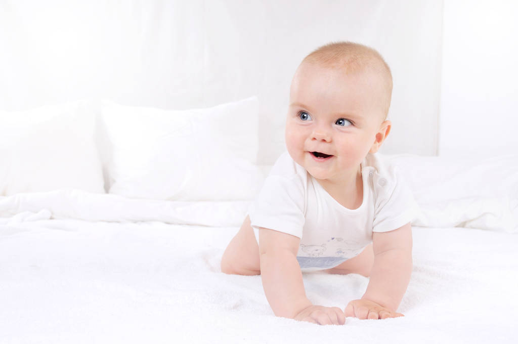Αξιολάτρευτο μωρό αγόρι σε λευκό ηλιόλουστη κρεβατοκάμαρα - Φωτογραφία, εικόνα