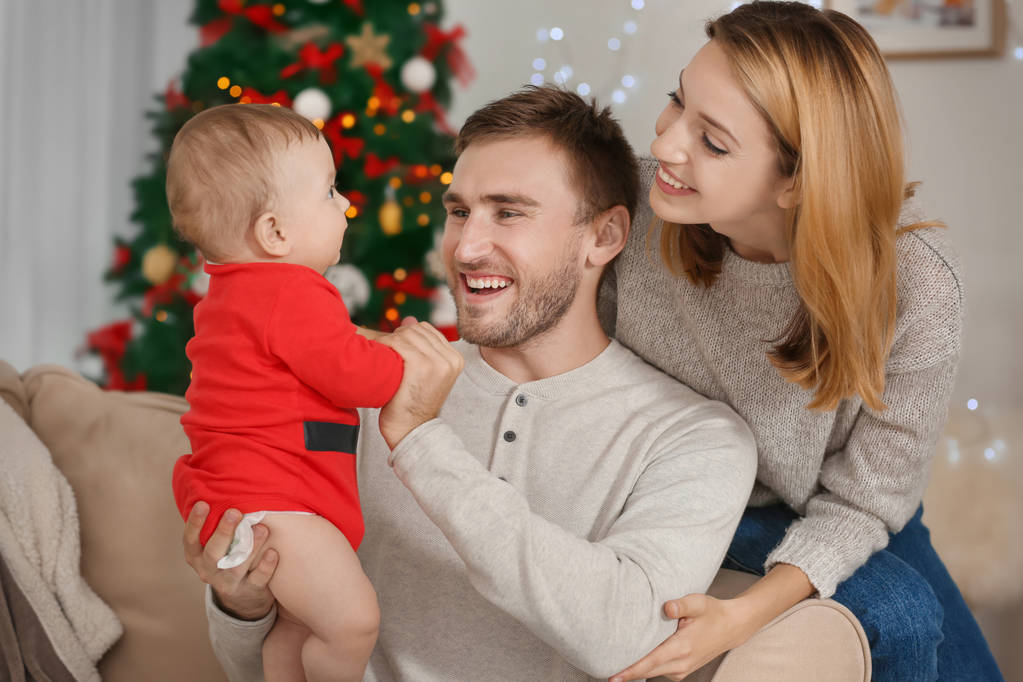 Gelukkige ouders met baby in ingerichte kamer voor Kerstmis - Foto, afbeelding