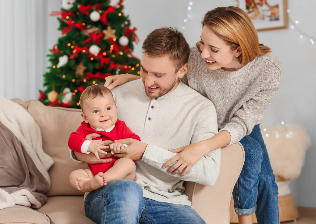 Genitori felici con bambino in camera decorata per Natale
 - Foto, immagini