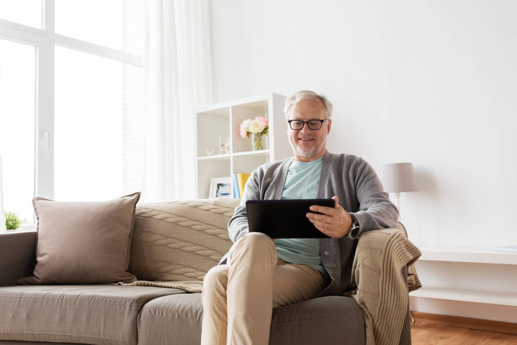 tablet pc を自宅のソファーに座っていた年配の男性 - 写真・画像
