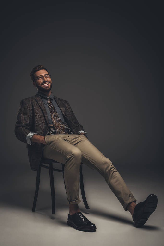 Smějící se muž v obleku, sedí na židli - Fotografie, Obrázek