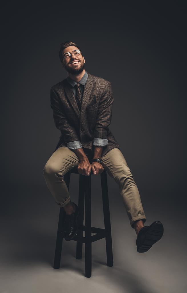 Smějící se muž v obleku sedí na stoličce - Fotografie, Obrázek