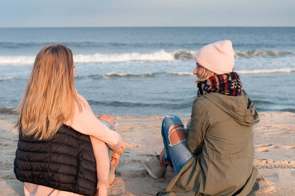 Przyjaciele. Dwie dziewczyny na morzu patrząc na plaży jesienią.   - Zdjęcie, obraz