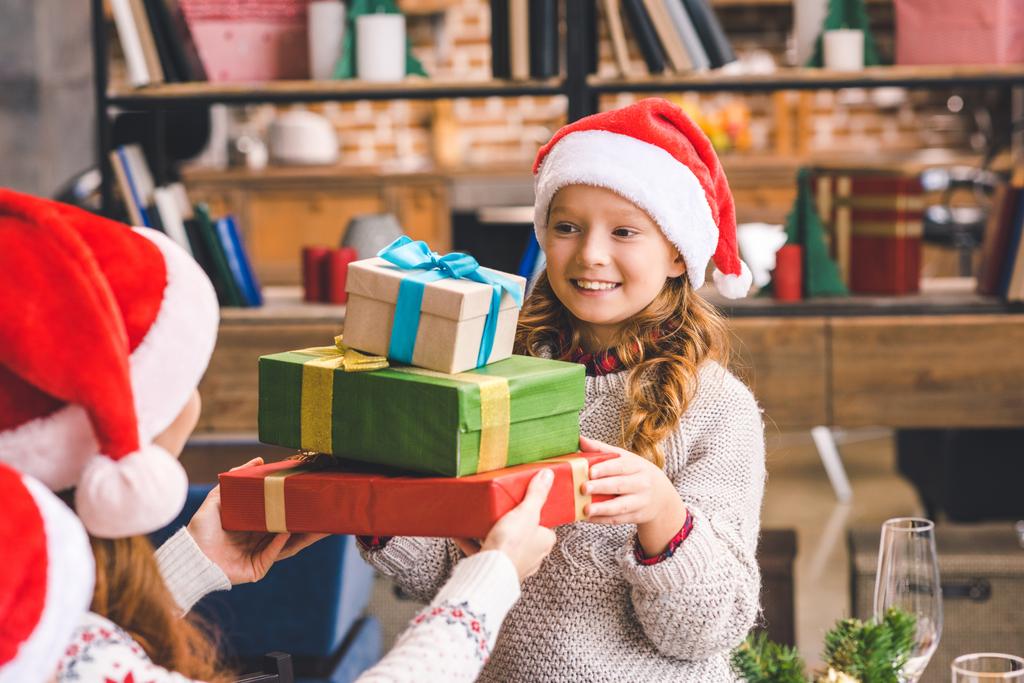 girl giving stack of presents to mother - Photo, Image