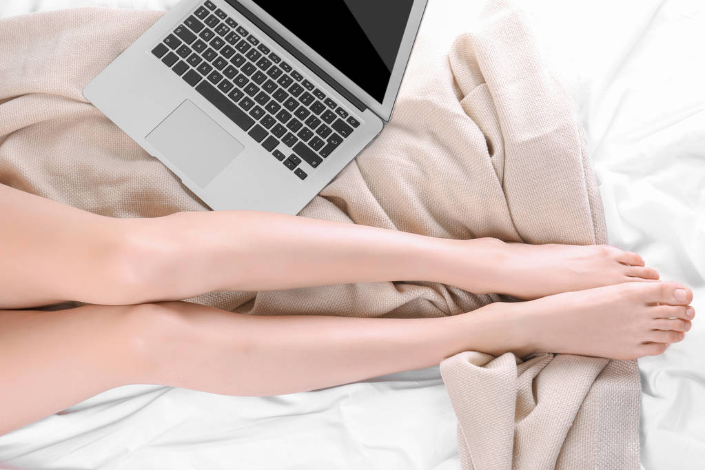 Giovane donna sul letto con computer portatile, vista dall'alto
 - Foto, immagini