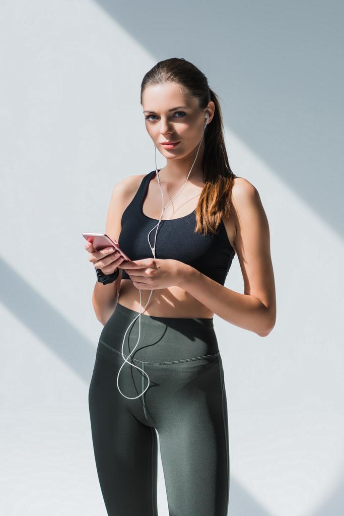 αθλήτρια στα ακουστικά χρησιμοποιώντας το smartphone - Φωτογραφία, εικόνα