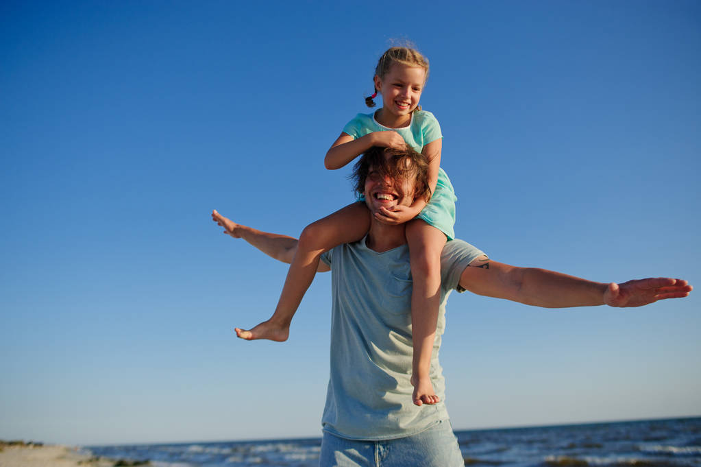 Joven alegre pasa tiempo con la pequeña hija junto al mar
. - Foto, imagen