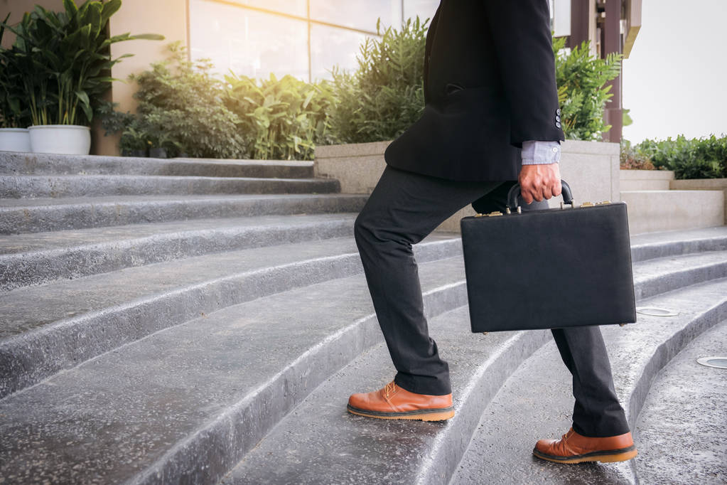 Businessman walking up the stairs and holding a briefcase in han - Photo, Image