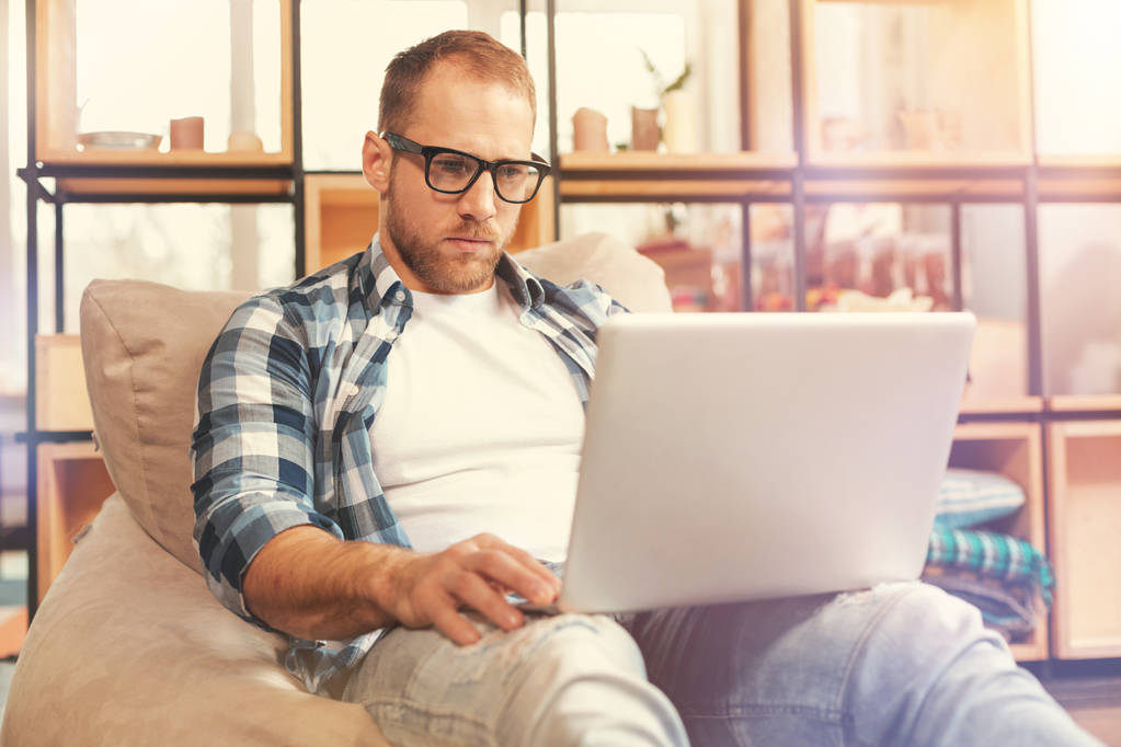 Sério jovem startupper vestindo óculos trabalhando no laptop
 - Foto, Imagem