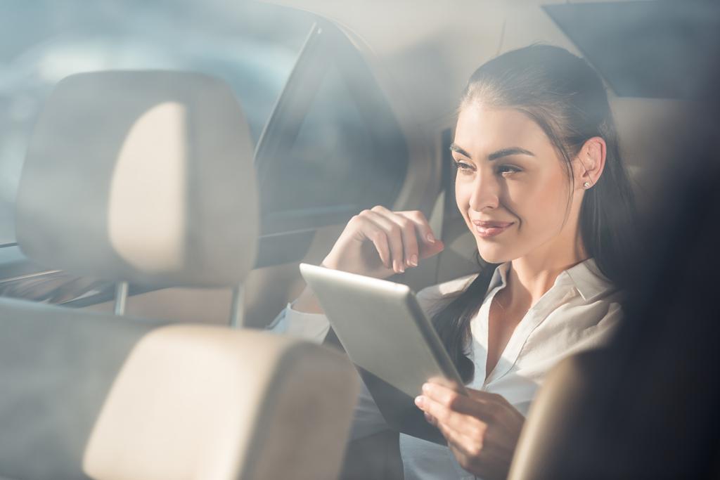 vrouw in auto met digitale tablet - Foto, afbeelding