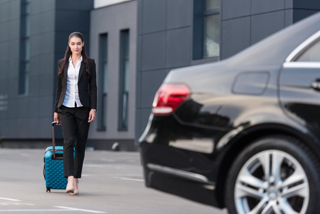 Woman walking with suitcase in parking lot - Photo, Image