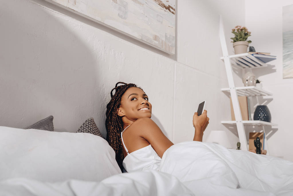 Donna utilizzando smartphone a letto - Foto, immagini