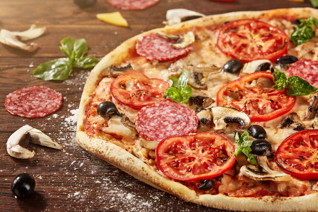 Świeża pizza z pomidorami, serem i grzybami na drewnianym stole - Zdjęcie, obraz