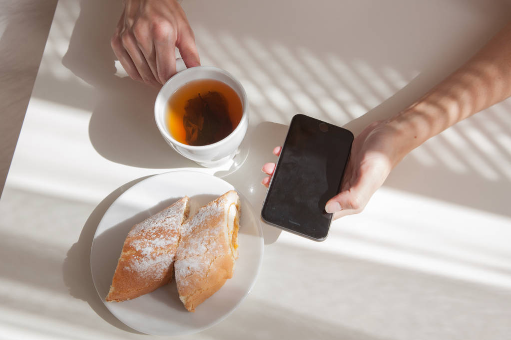 Csésze tea és smartphone tartó női  - Fotó, kép