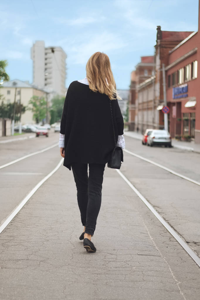 Bielorrússia, Minsk 25 de agosto de 2017 - Hipster menina andando no centro da rua em poncho preto e jeans
 - Foto, Imagem