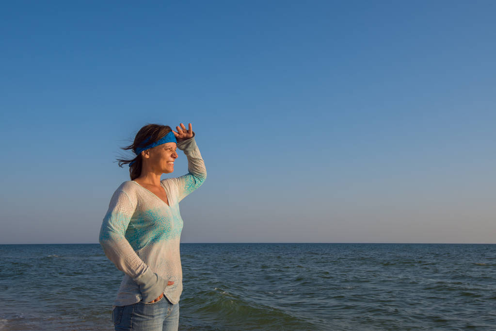 Šťastná žena cestujícím stojí osamoceně na pobřeží moře - Fotografie, Obrázek