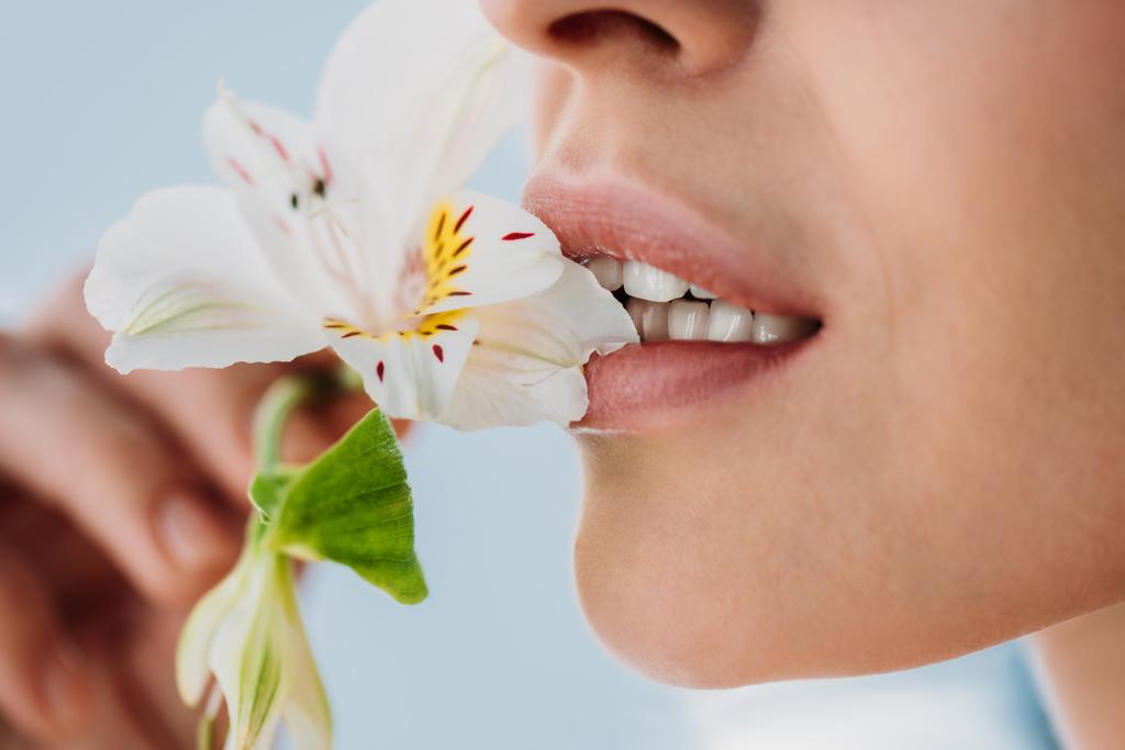 nainen, jolla on tuore iho, jossa on lilja huulissa
 - Valokuva, kuva