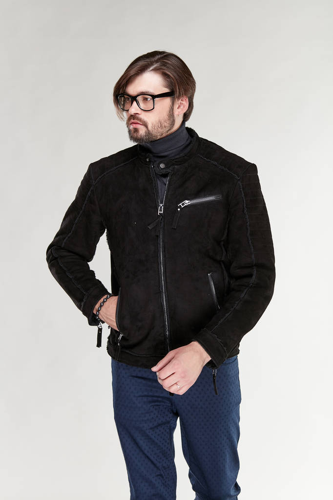Atractivo joven sexy hombre modelo con barba y gafas posando en chaqueta marrón oscuro y pantalones azul oscuro en estudio de luz
  - Foto, Imagen