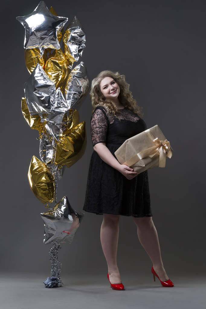 Plus tamanho mulher em preto dres com caixa de presente e balões em fundo cinza
 - Foto, Imagem