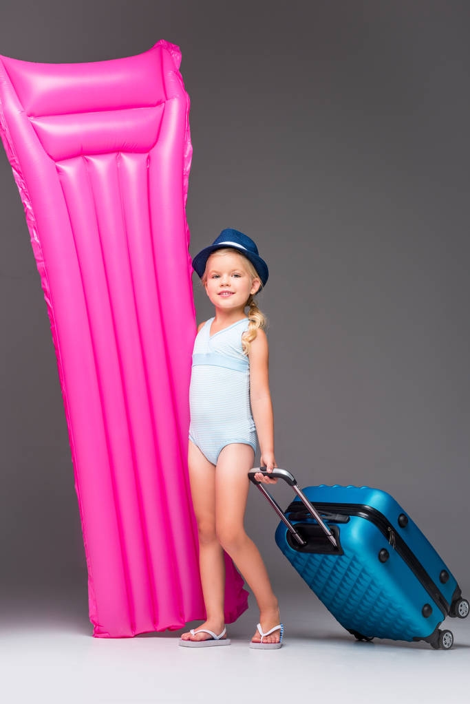 criança com mala e colchão de natação
 - Foto, Imagem
