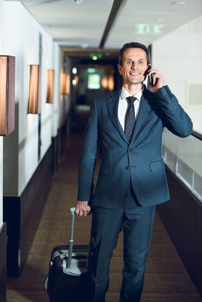 hombre de negocios caminando en el hotel con teléfono inteligente
 - Foto, Imagen