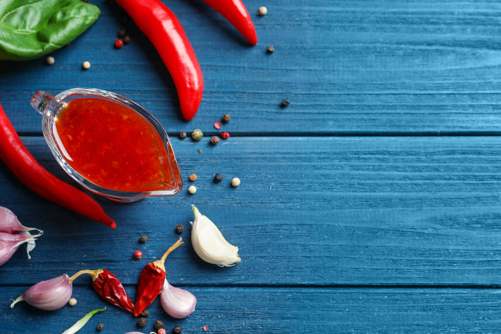 Samenstelling met chili saus, peper peulen en granen op houten achtergrond - Foto, afbeelding