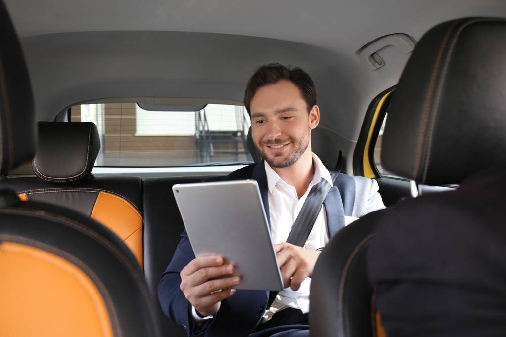 Knappe man met tablet zitten in taxi-auto - Foto, afbeelding