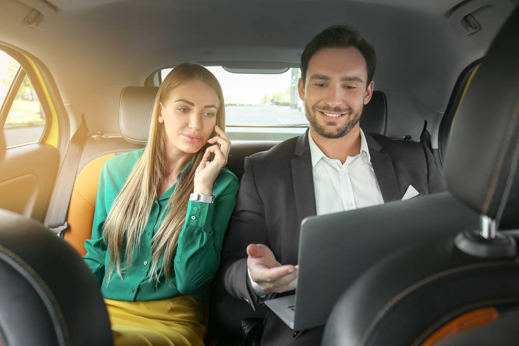 Hermosa mujer hablando por teléfono y hombre guapo con portátil sentado en el asiento trasero en el coche de taxi
 - Foto, imagen