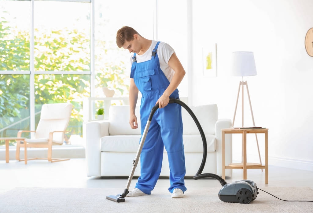 Hombre limpieza alfombra blanca con vacío en la sala de estar
 - Foto, Imagen