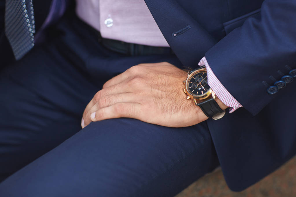 Una vista de la mano mans con un reloj negro en el fondo de un traje mans azul
. - Foto, Imagen