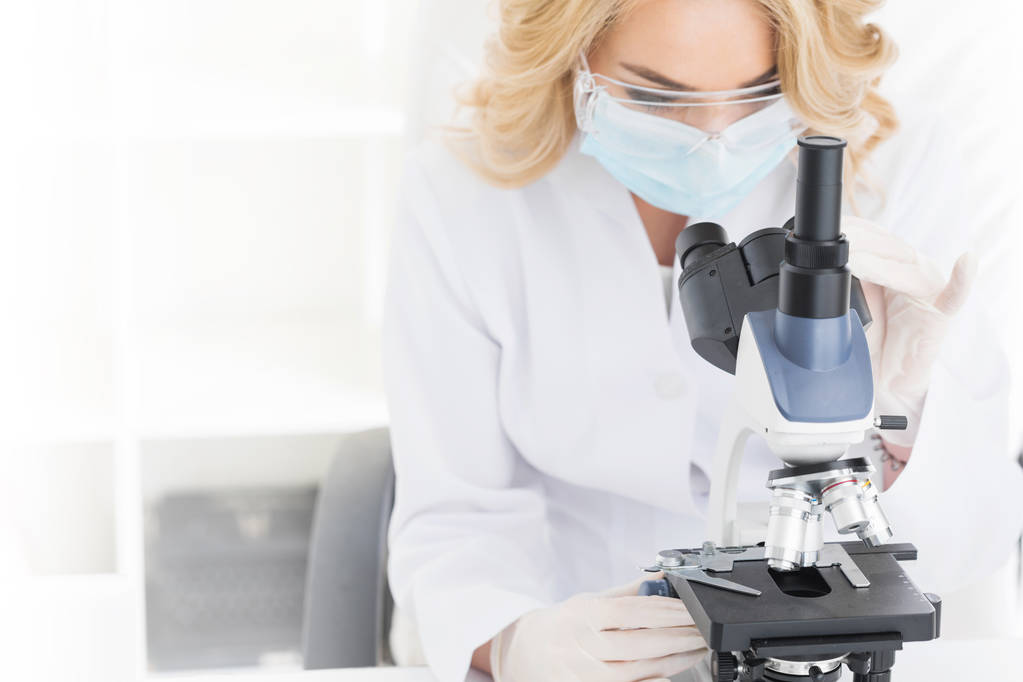 Médico femenino mirando a través de un microscopio
 - Foto, imagen