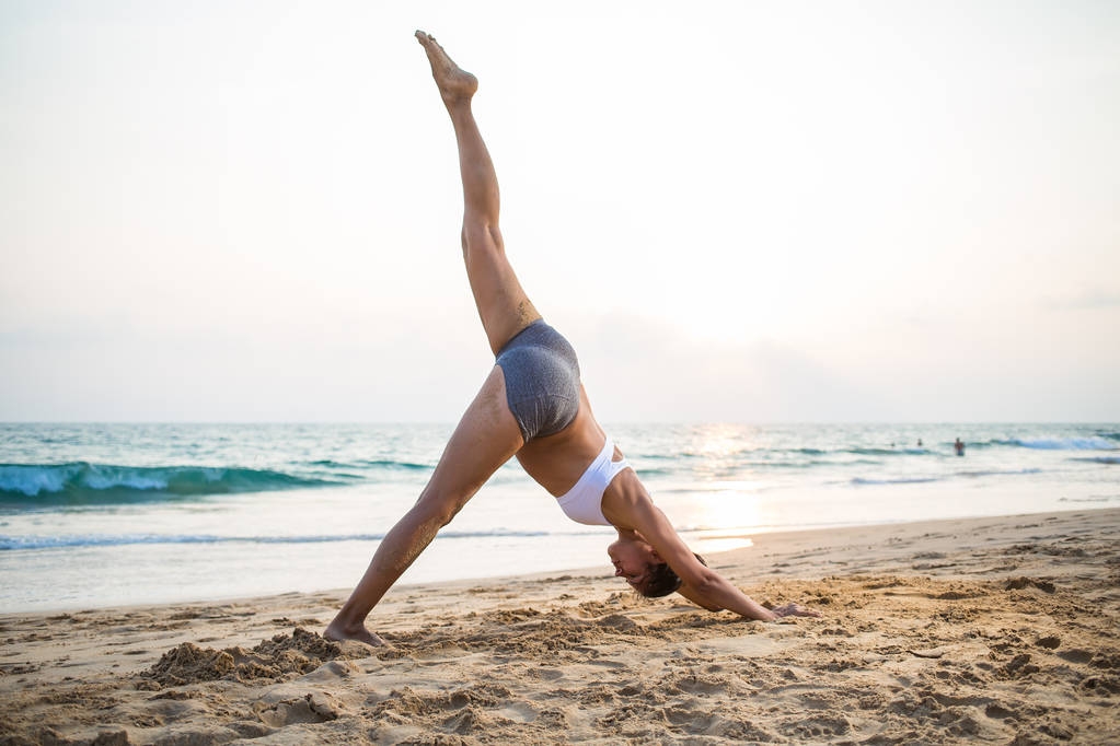 Mujer embarazada de aspecto natural practicando yoga en la orilla del mar a
 - Foto, Imagen