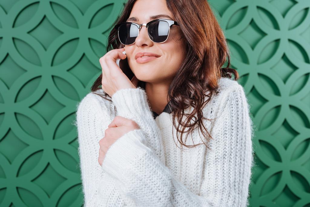  Γυναίκα στο πουλόβερ και τα γυαλιά ηλίου που μιλάει με το smartphone - Φωτογραφία, εικόνα