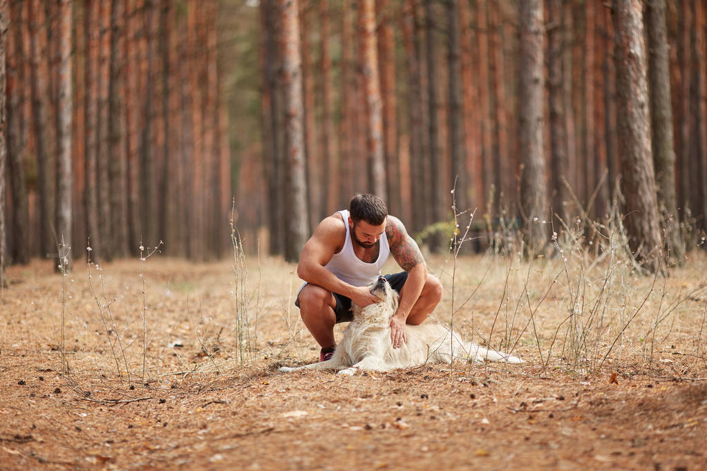 Un hombre acariciando a un perro en el bosque para dar un paseo
 - Foto, Imagen