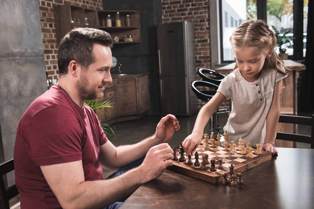 Tochter arrangiert Schachfiguren - Foto, Bild
