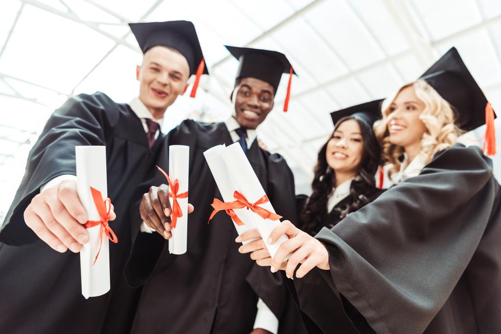 estudiantes multiétnicos que muestran diplomas
 - Foto, Imagen