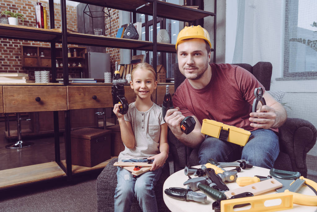 Père et fille posant avec des outils jouets
  - Photo, image