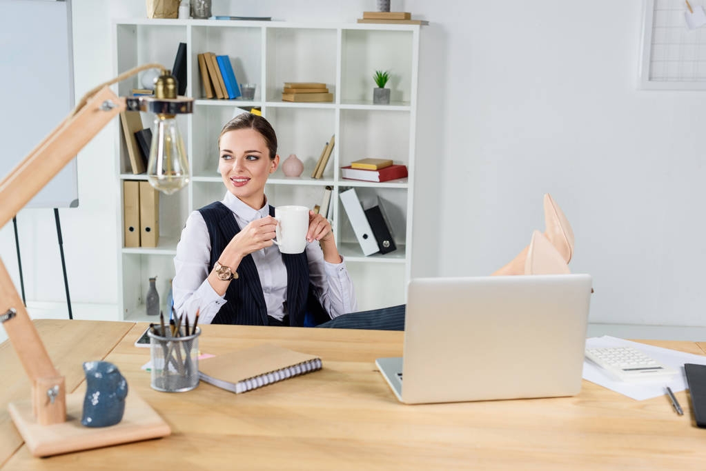 zakenvrouw met kopje koffie in kantoor - Foto, afbeelding