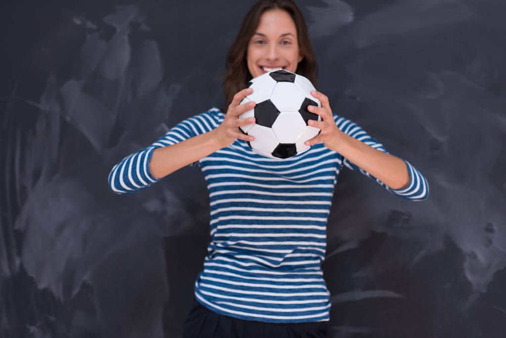 mujer sosteniendo una pelota de fútbol delante de la pizarra de dibujo
 - Foto, Imagen
