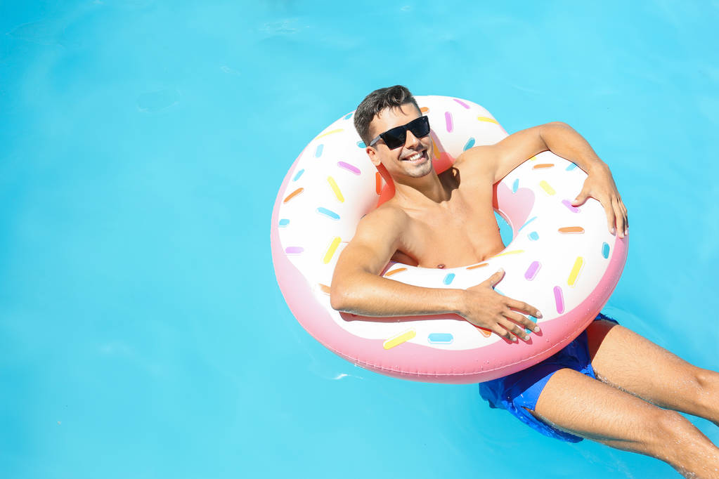 Jonge man met een opblaasbare donut   - Foto, afbeelding