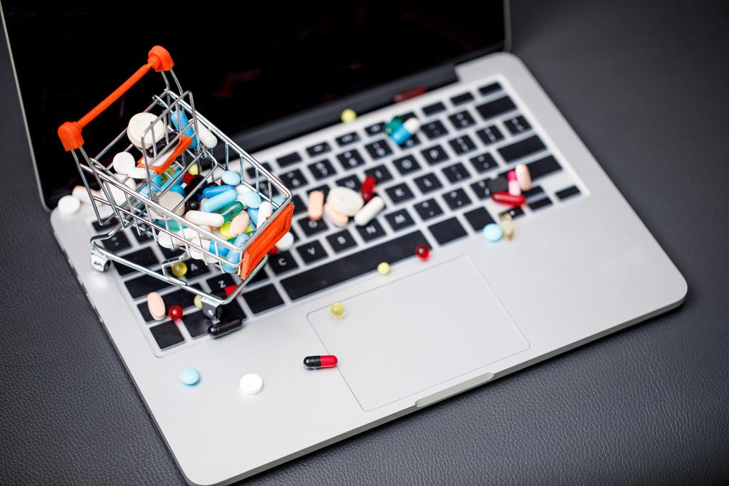 laptop e pillole nel piccolo carrello della spesa
 - Foto, immagini