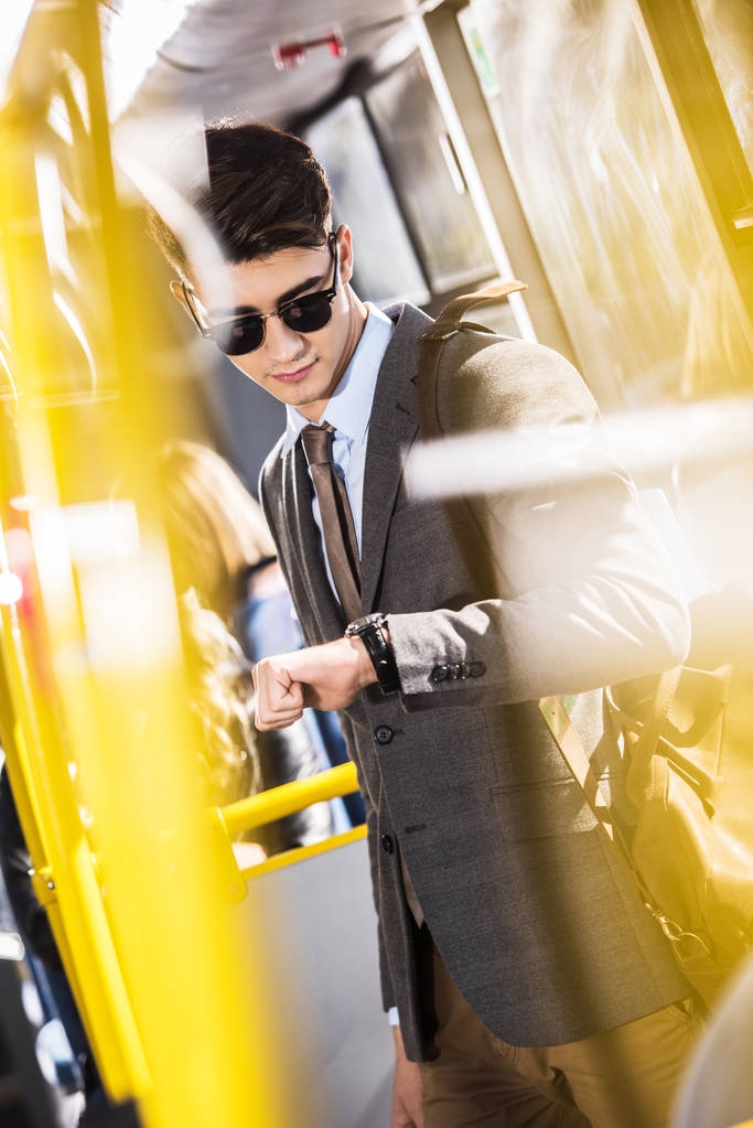 hombre de negocios revisando reloj de pulsera en autobús
  - Foto, imagen