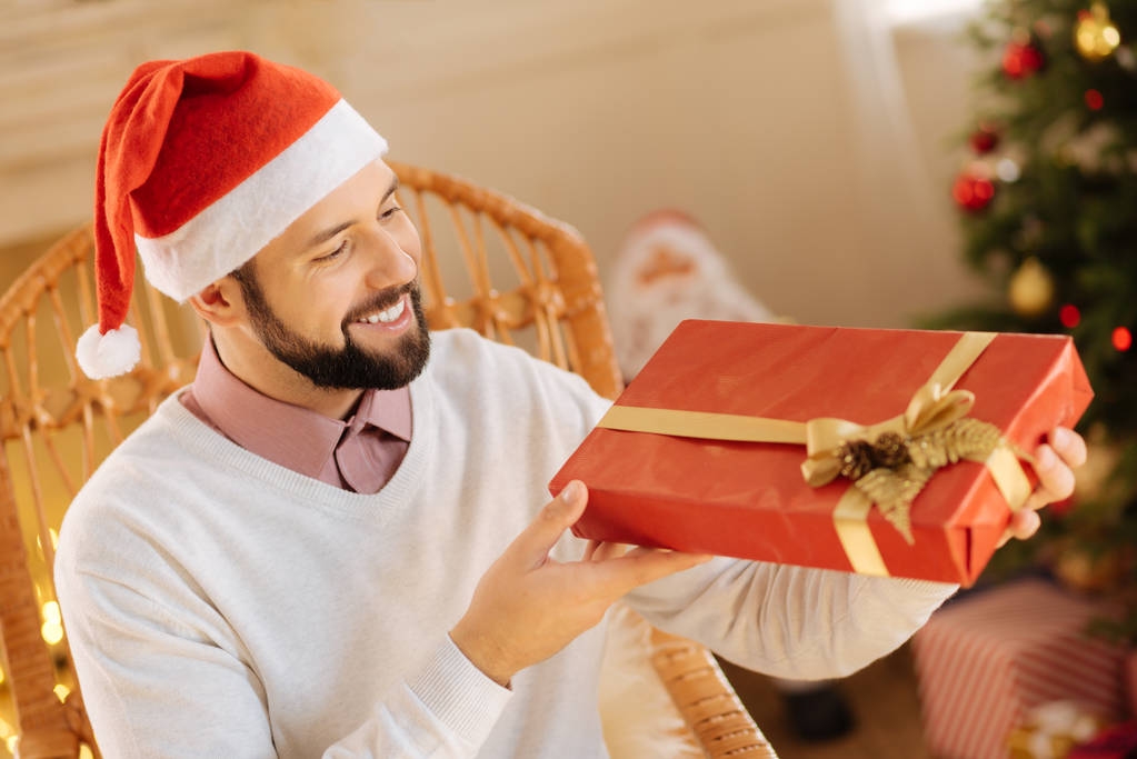 Щасливий чоловік вивчає подарункову коробку в руках
 - Фото, зображення